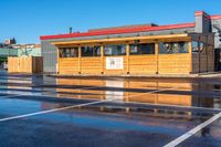 a wet car parking lot full of a small wooden building with a sign attached to it's roof