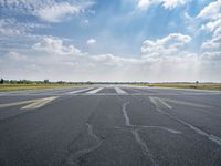 an empty runway with the sun shining brightly behind it to reveal a clear blue sky