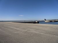 a parking space sitting on the side of a road next to the ocean with a boat coming up and a dock