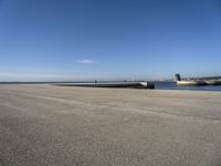 a parking space sitting on the side of a road next to the ocean with a boat coming up and a dock