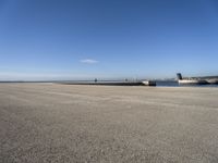 a parking space sitting on the side of a road next to the ocean with a boat coming up and a dock