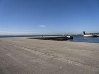 a parking space sitting on the side of a road next to the ocean with a boat coming up and a dock