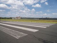 an airport runway and the shadow on the pavement and the ground and clouds over the road