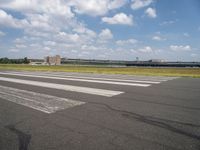 an airport runway and the shadow on the pavement and the ground and clouds over the road