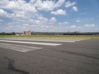 an airport runway and the shadow on the pavement and the ground and clouds over the road