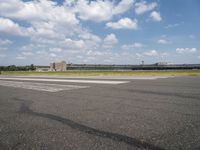 an airport runway and the shadow on the pavement and the ground and clouds over the road