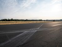 the person in white jacket on a motorcycle riding in an empty runway near some trees