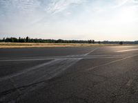 the person in white jacket on a motorcycle riding in an empty runway near some trees