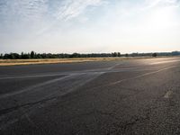 the person in white jacket on a motorcycle riding in an empty runway near some trees