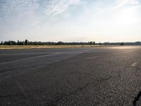 the person in white jacket on a motorcycle riding in an empty runway near some trees