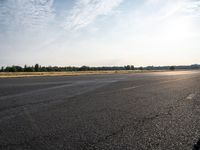 the person in white jacket on a motorcycle riding in an empty runway near some trees