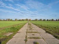 a pathway in a rural area with no cars on it and a blue sky above