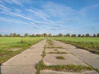 a pathway in a rural area with no cars on it and a blue sky above