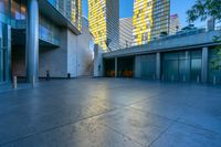 a concrete area with buildings and sky in the background at dusk, including two glass skyscrapers