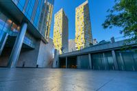 a concrete area with buildings and sky in the background at dusk, including two glass skyscrapers