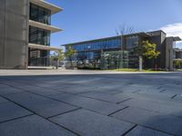 there are some glass windows in this office building architecture and the sidewalk on the right is an alley with lots of grass