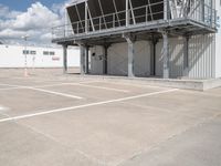 an empty parking lot with stairs going up to an industrial area, with a sky background