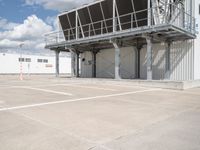 an empty parking lot with stairs going up to an industrial area, with a sky background