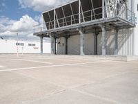 an empty parking lot with stairs going up to an industrial area, with a sky background