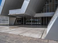 a white building with several steps and large glass panels in the facade is a mosaic that depicts a man