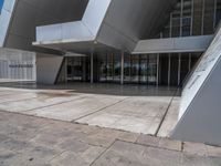 a white building with several steps and large glass panels in the facade is a mosaic that depicts a man