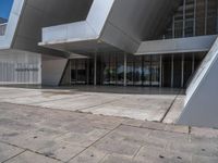 a white building with several steps and large glass panels in the facade is a mosaic that depicts a man