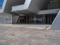 a white building with several steps and large glass panels in the facade is a mosaic that depicts a man