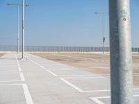 a parking lot with street lamps and poles at the end of it's row