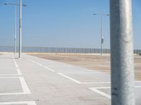 a parking lot with street lamps and poles at the end of it's row