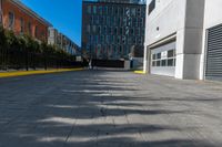 a sidewalk is in the middle of some buildings with a man walking down it on the street