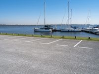 a parking lot with lots of boats on the water behind it and one of the parked cars on the shore