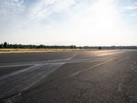 a young woman wearing a pink shirt is flying a kite in the distance while on the tarmac