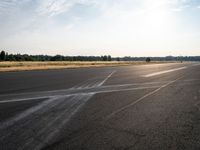 a young woman wearing a pink shirt is flying a kite in the distance while on the tarmac