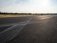 a young woman wearing a pink shirt is flying a kite in the distance while on the tarmac