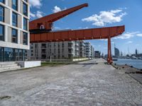 an image of a city setting with the water in front of it, and a large crane lifting people on to the side