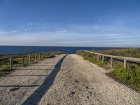 a gravel path with white pebbles and wood railings over looking the ocean and land