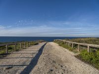 a gravel path with white pebbles and wood railings over looking the ocean and land