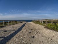 a gravel path with white pebbles and wood railings over looking the ocean and land