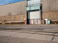 a large warehouse building sitting next to a road in front of it and graffiti on the wall