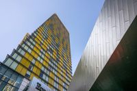 two buildings side by side, one of which is a yellow glass building and the other is a gray glass tower