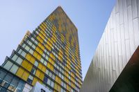 two buildings side by side, one of which is a yellow glass building and the other is a gray glass tower