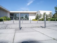 a building with a parking meter sitting in the middle of a courtyard with poles to provide a sidewalk way