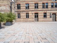 a bricked up courtyard and green planters with plants in the center of it