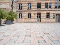 a bricked up courtyard and green planters with plants in the center of it