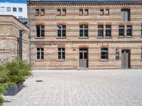 a bricked up courtyard and green planters with plants in the center of it