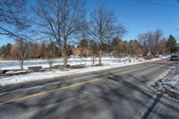 a car travels down an empty road with lots of snow on the ground and trees in the background