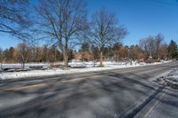 a car travels down an empty road with lots of snow on the ground and trees in the background