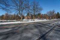 a car travels down an empty road with lots of snow on the ground and trees in the background