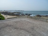 the empty parking lot has a water feature on it's wall and beach area with rock formations