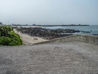 the empty parking lot has a water feature on it's wall and beach area with rock formations